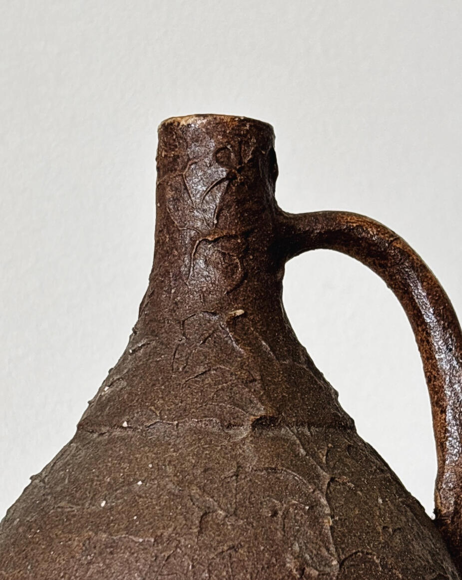 Close-up of curated ceramic jug with textured surface in deep brown tones